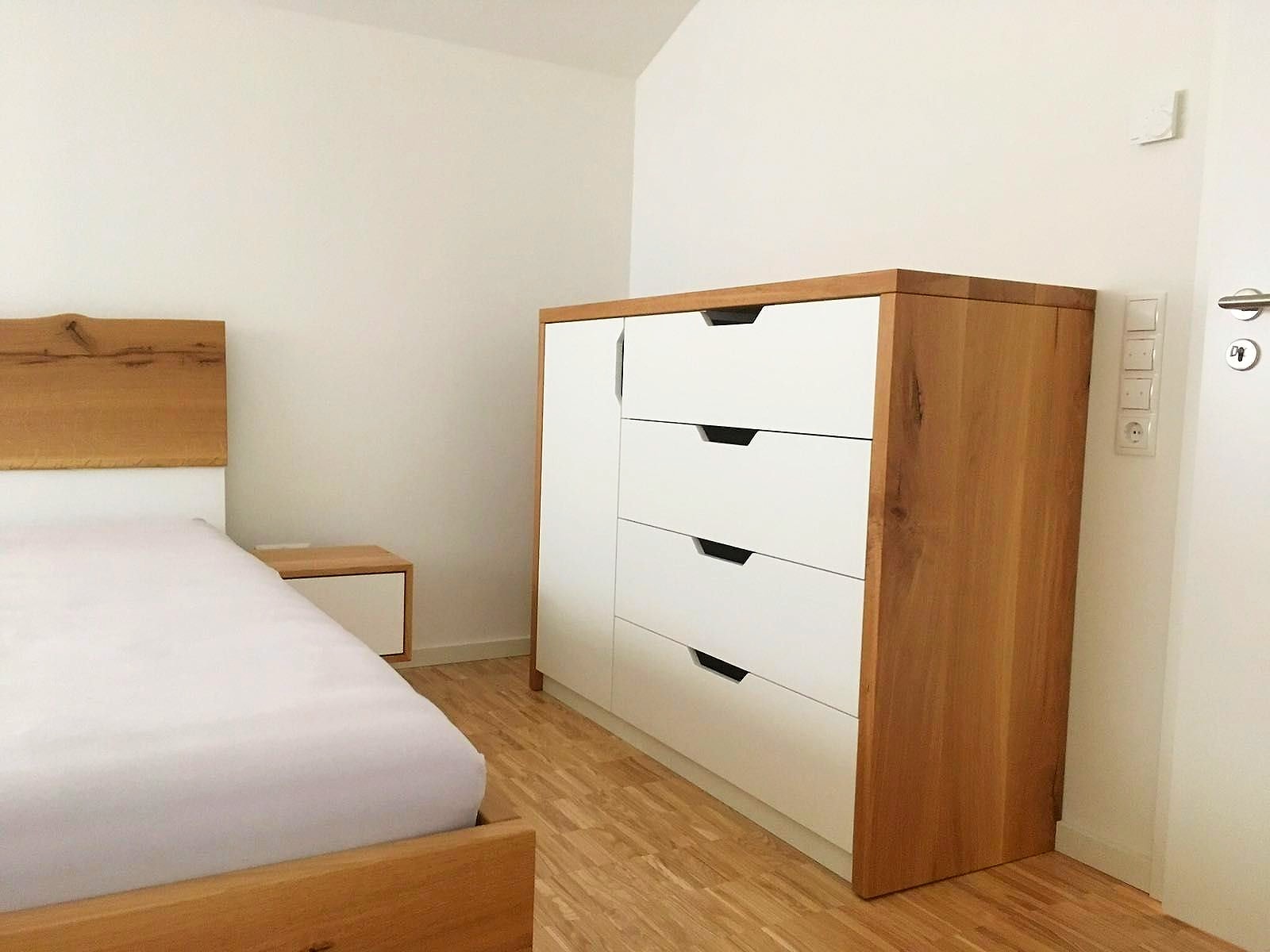 Kommode mit Eichenkorpus und eingefrästen Griffmulden im Schlafzimmer mit Dachschräge.