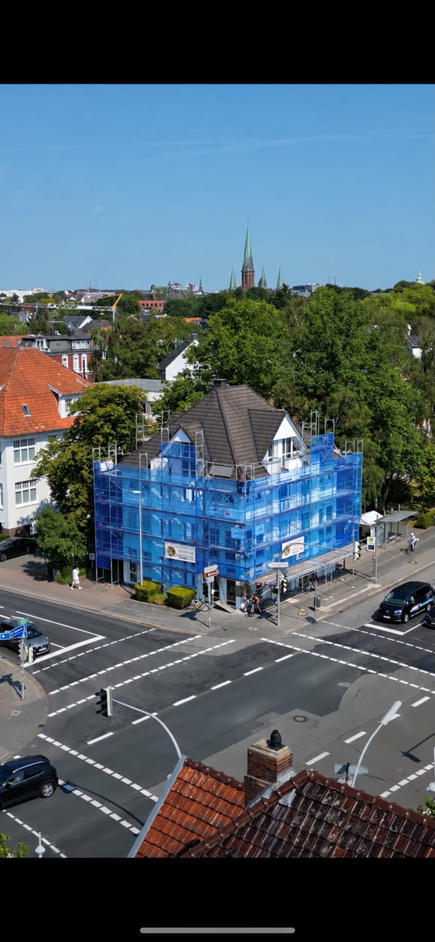 Eingerüstetes Eckgebäude in Oldenburg mit Walmdach und Gauben, im Hintergrund die Lambertikirche.