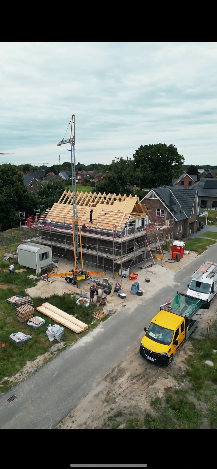 Ein frisch aufgestellter Holzdachstuhl mit Sparren und Schalung zeigt, worauf Dämmung und Eindeckung später aufbauen.