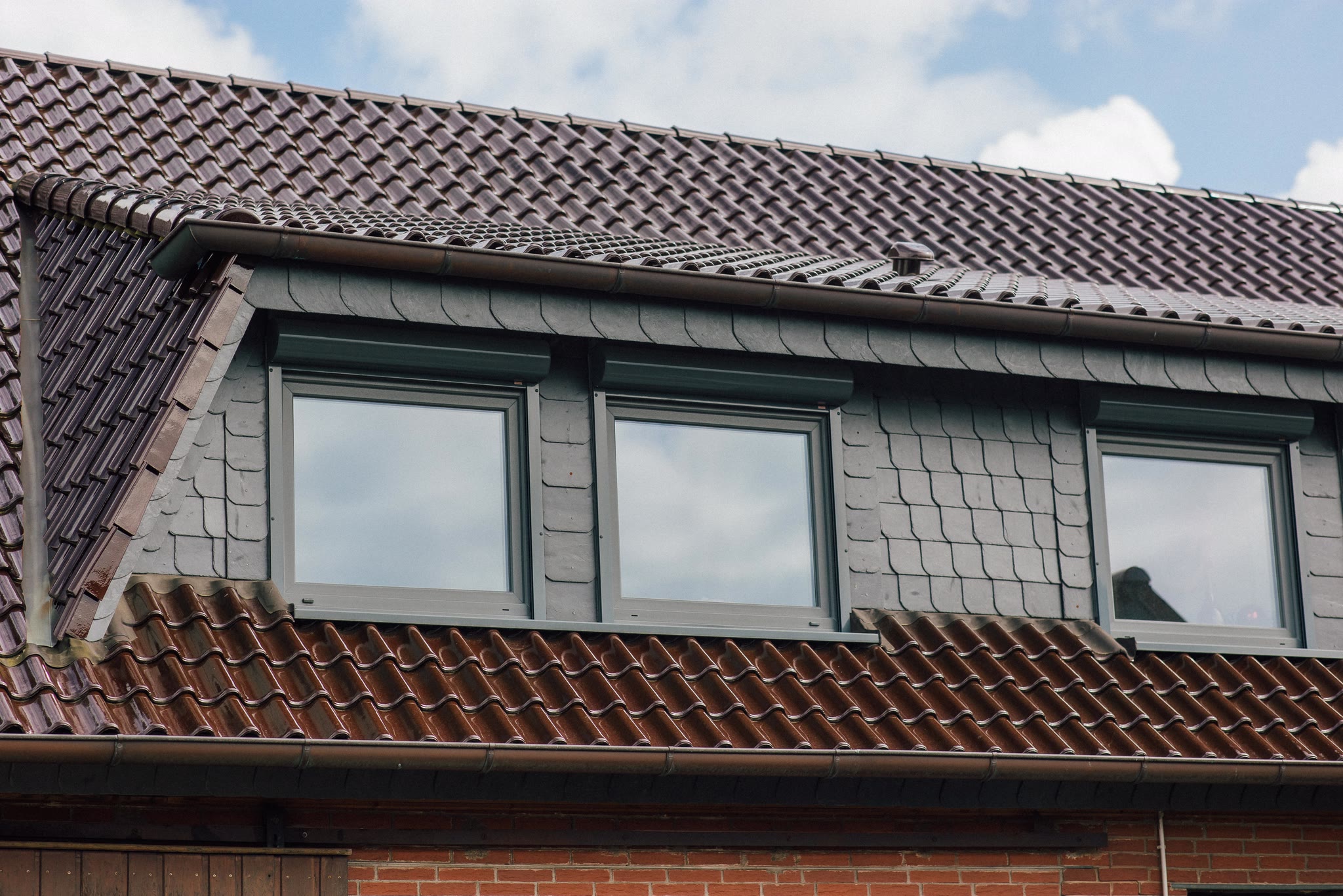 Neues graues Fenster mit farblich passendem Vorbaurollladenkasten an einem sanierten Wohnhaus in Lippe