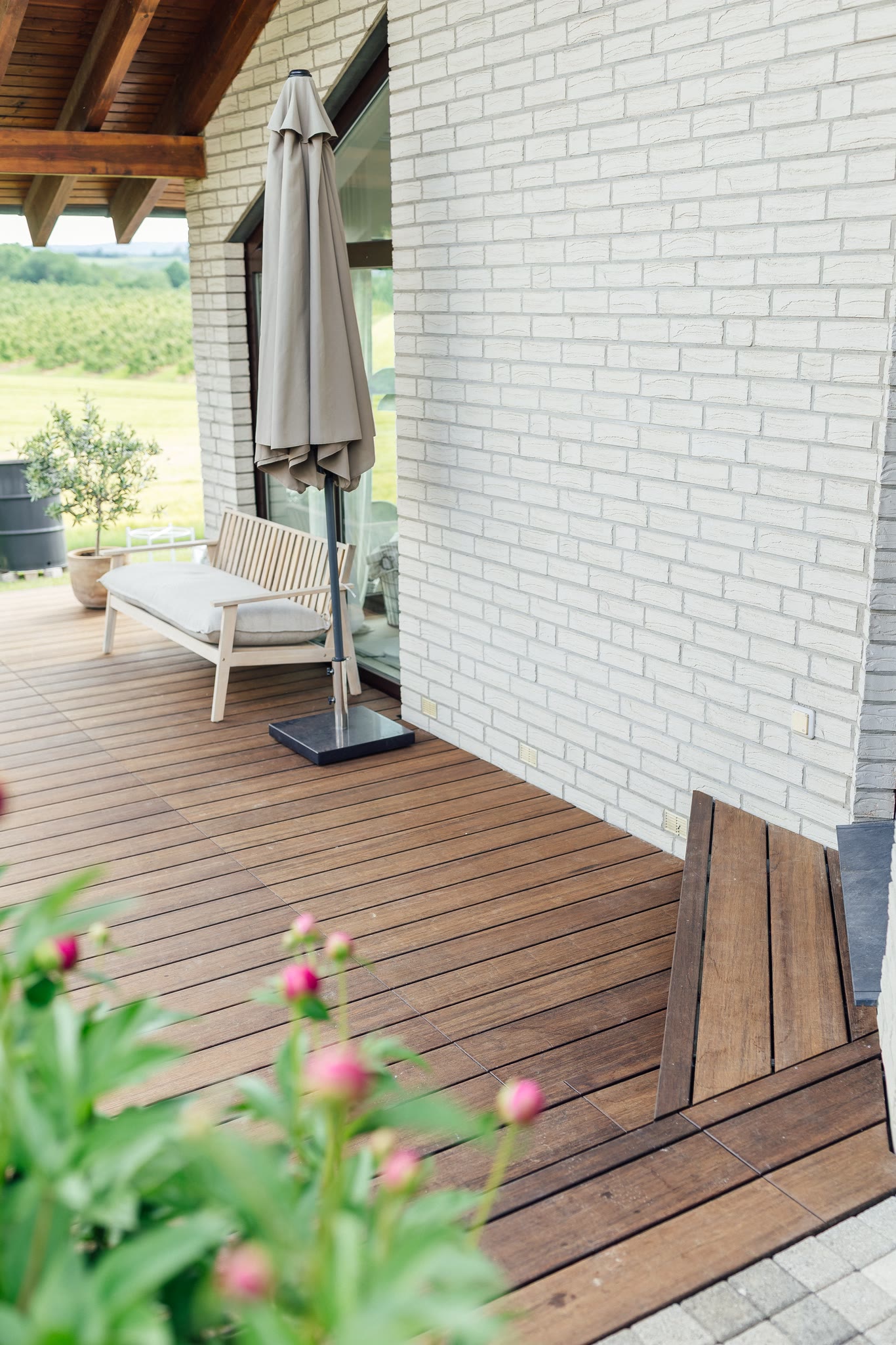 Fertig: die Terrasse entlang der weißen Klinkerfassade mit Sitzplatz im überdachten Bereich.