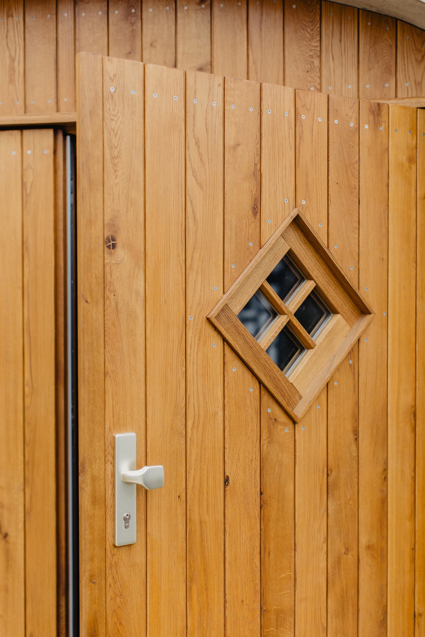 Rautenförmiges Sprossenfenster mit Kreuzsprossen im eingebauten Torflügel.
